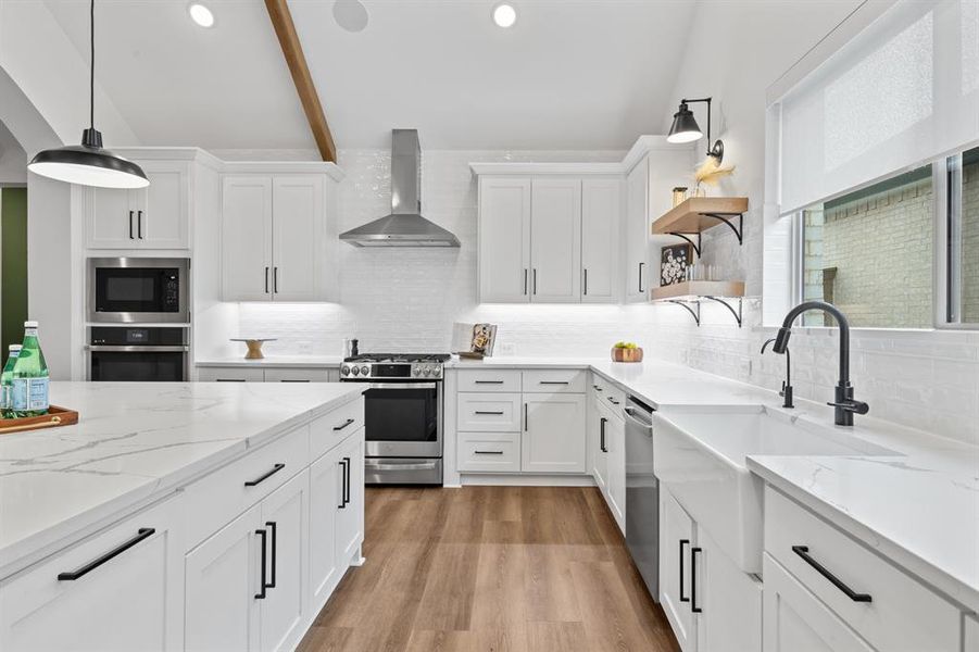 Kitchen featuring open shelves, white cabinets, light stone counters, and decorative light fixtures