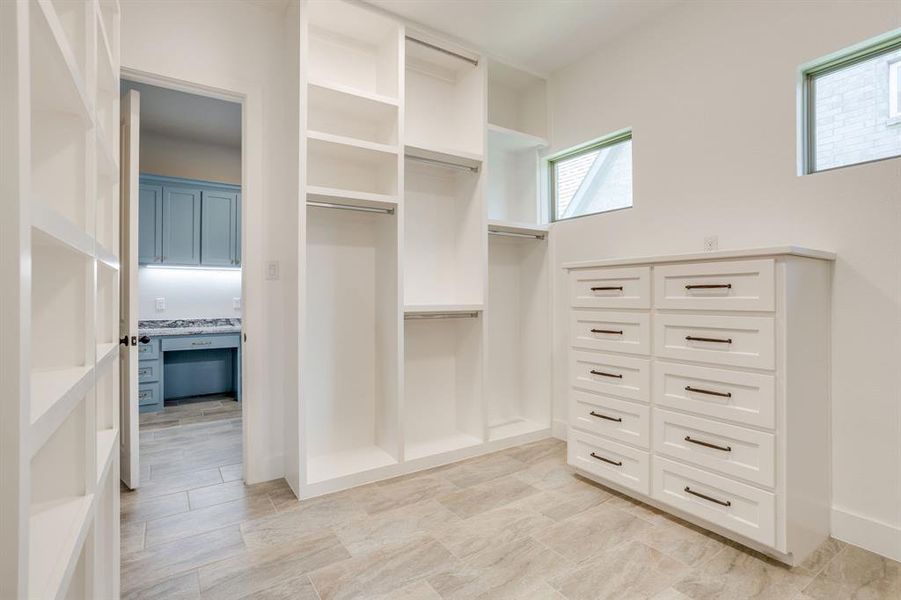 Built-in shelving and cabinetry featuring hanging rods, display shelves, and a large dresser with dark hardware
