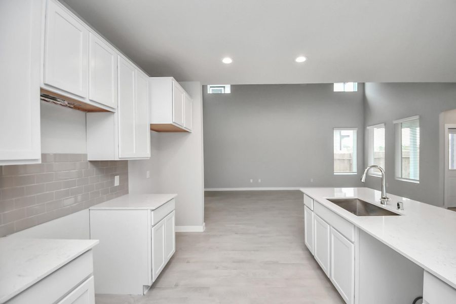 This generously spacious layout boasts high ceilings, soft-close cabinets, granite countertops, stainless steel appliances (to be installed), a sleek tile backsplash, and recessed lighting. An extended counter area adds an extra layer of functionality. Sample photo of completed home with similar floor plan. Actual colors and selections may vary.