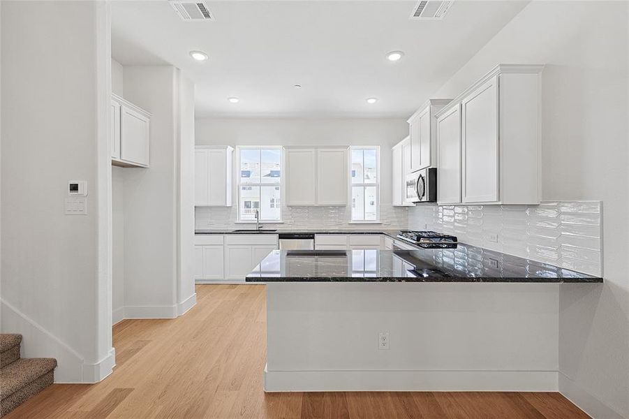 Kitchen featuring white cabinetry, kitchen peninsula, and stainless steel appliances Kitchen featuring white cabinetry, kitchen peninsula, and stainless steel appliances