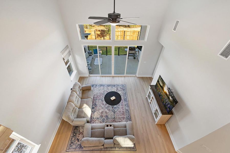 Towering ceilings and broad glass doors define this airy living space with light-toned wood floors.