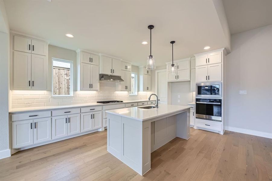 Kitchen featuring stainless steel appliances, under cabinet range hood, recessed lighting, backsplash, and white cabinetry