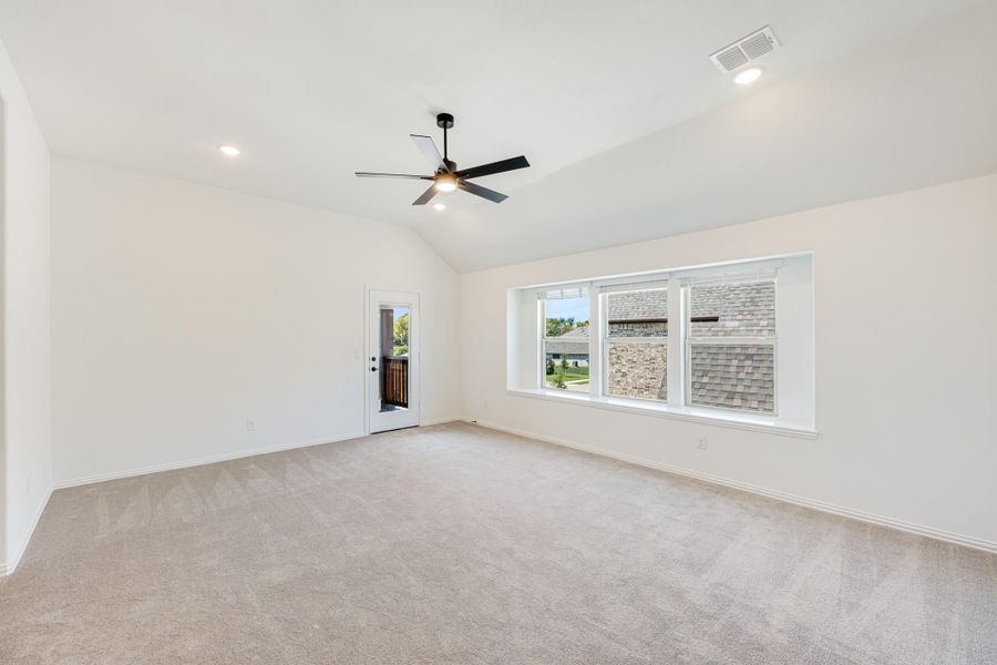 Empty living room with vaulted ceiling, ceiling fan, carpet flooring, and large window with backyard door Empty living room with vaulted ceiling, ceiling fan, carpet flooring, and large window with backyard door