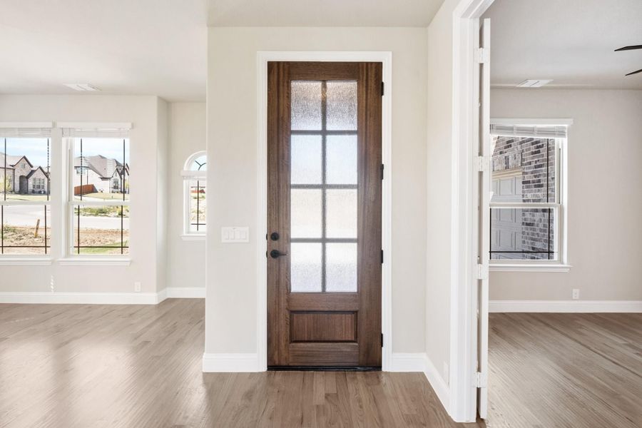Entryway with dark wood front door featuring glass panels, white trim, and hardwood floors