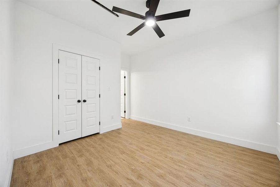 Unfurnished bedroom with light wood-style flooring, ceiling fan, and a closet