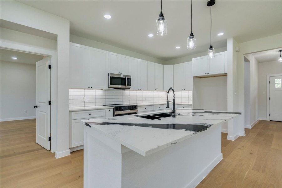 A well-appointed kitchen showcasing a spacious island with ample counter & storage space.