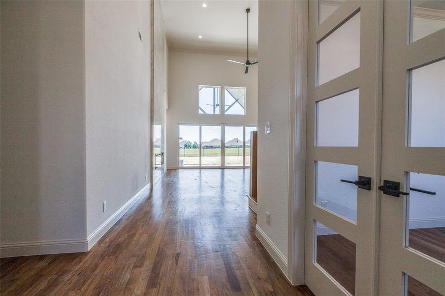 Hall featuring a high ceiling, ornamental molding, dark wood-type flooring, and french doors