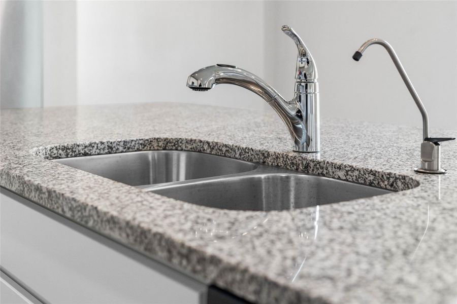 This modern kitchen island features a polished granite countertop with an undermount double-bowl stainless steel sink, complemented by a chrome pull-out faucet and a dedicated reverse osmosis drinking water tap.