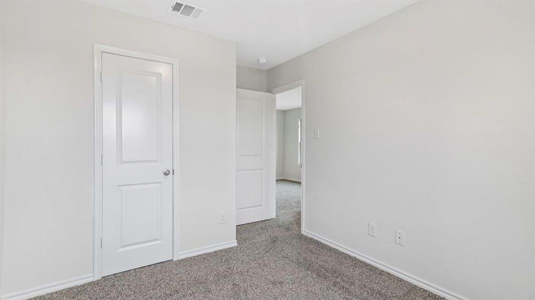 Bright room featuring light gray walls, gray carpet, white baseboards, and white paneled doors