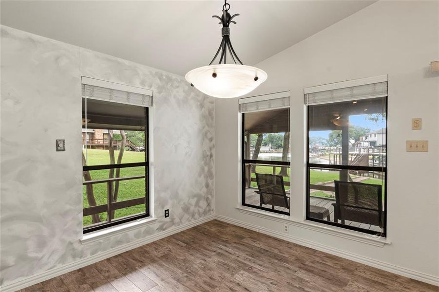 Open-concept living space with wood-grain porcelain tile, flowing seamlessly from kitchen to dining—perfect for entertaining or relaxing with lake views.