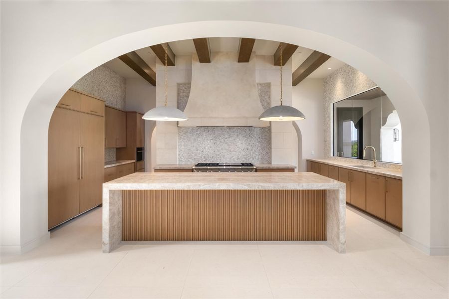 Kitchen features stone-topped island with waterfall edge, beams, mosaic tiled walls, walk-in pantry  and high end appliances.