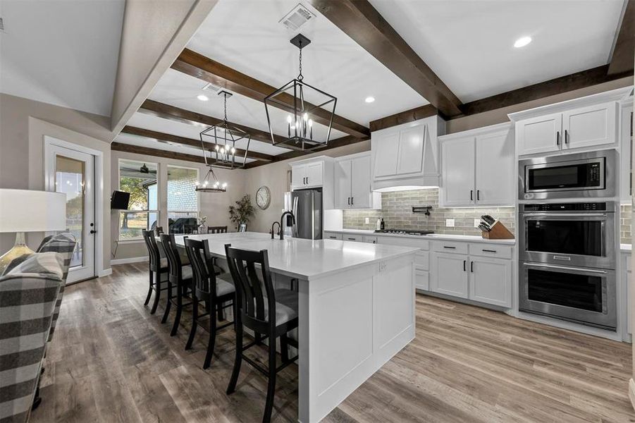 Kitchen with white cabinetry, beamed ceiling, and appliances with stainless steel finishes