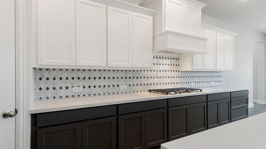 Kitchen featuring white cabinets, tasteful backsplash, stainless steel gas stovetop, and premium range hood