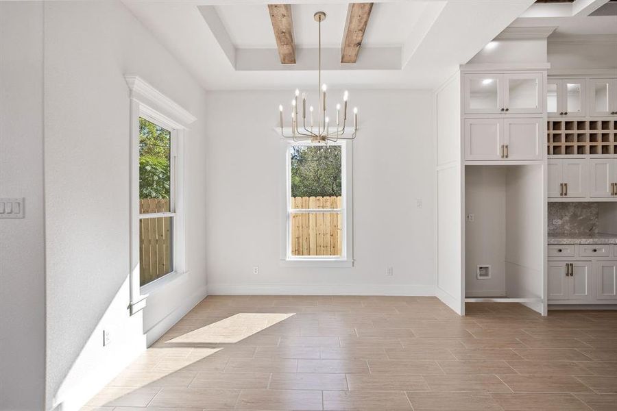 Unfurnished dining area with beamed ceiling, a chandelier, and wood finish floors