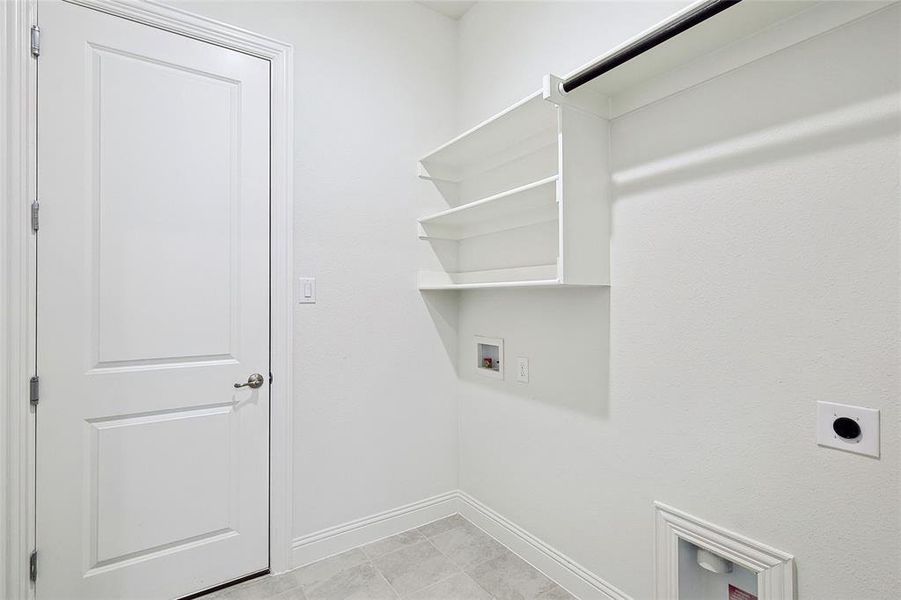 Clothes washing area featuring hookup for a washing machine, electric dryer hookup, and light tile patterned flooring