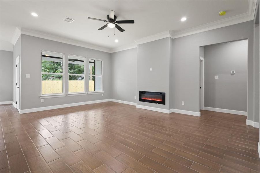 Unfurnished living room with ceiling fan, dark hardwood / wood-style floors, and ornamental molding