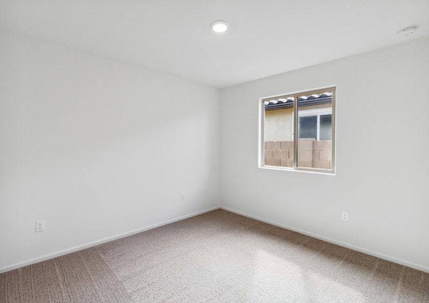 Secondary bedroom with tan carpet and recessed lighting.