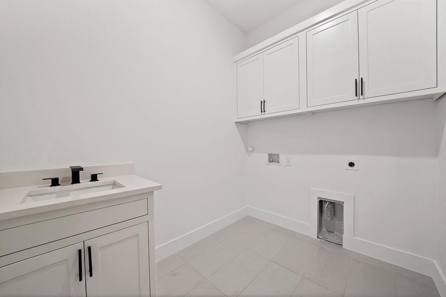Laundry area with cabinet space, hookup for an electric dryer, light tile patterned flooring, hookup for a washing machine, and gas dryer hookup Laundry area with cabinet space, hookup for an electric dryer, light tile patterned flooring, hookup for a washing machine, and gas dryer hookup