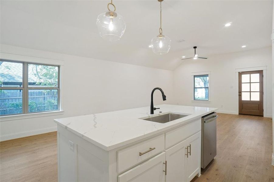 Kitchen with white cabinetry, light wood-style flooring, recessed lighting, open floor plan, and light stone countertops