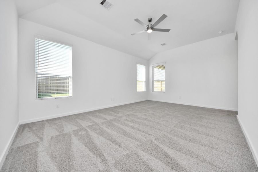 Escape and relax in the exquisite primary suite, a haven to unwind after a long day. The spacious room, located on first floor, boasts plush carpeting, soothing paint tones, high ceilings, and expansive windows adorned with privacy blinds. Sample photo of completed home with similar floor plan. Actual colors and selections may vary.