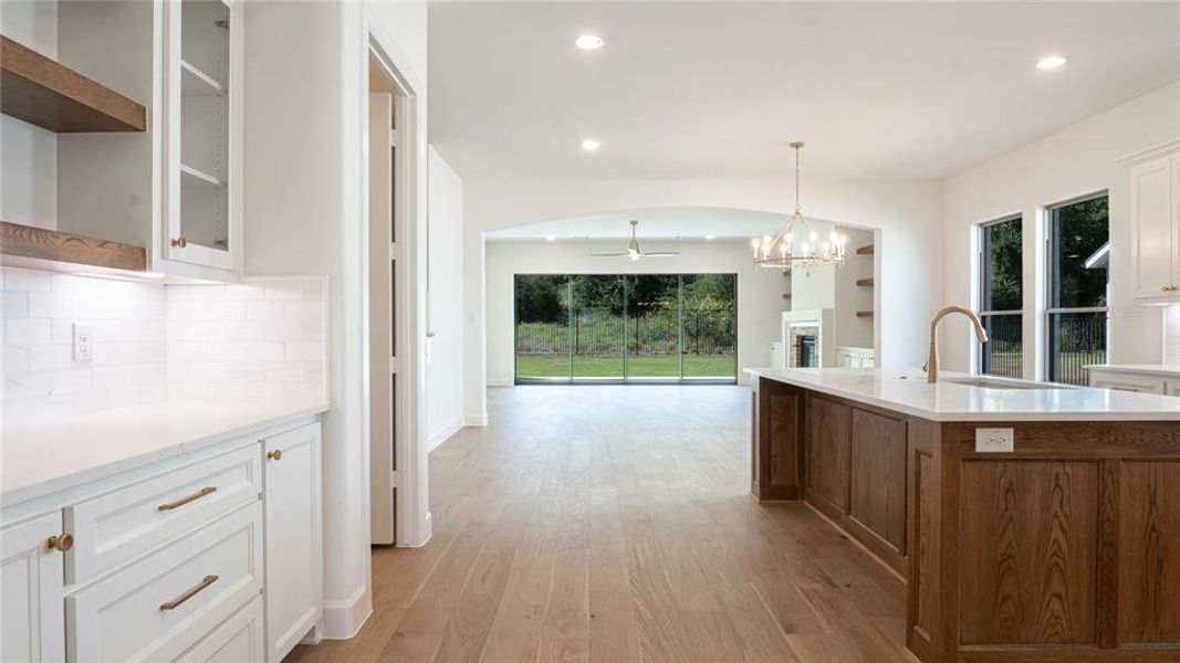 Kitchen with a chandelier, light wood finished floors, a ceiling fan, a fireplace, and recessed lighting Kitchen with a chandelier, light wood finished floors, a ceiling fan, a fireplace, and recessed lighting