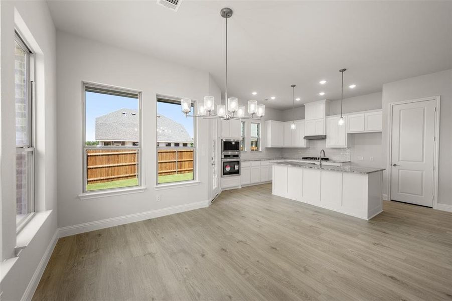 Kitchen featuring light wood-style floors, white cabinets, recessed lighting, backsplash, and pendant lighting Kitchen featuring light wood-style floors, white cabinets, recessed lighting, backsplash, and pendant lighting