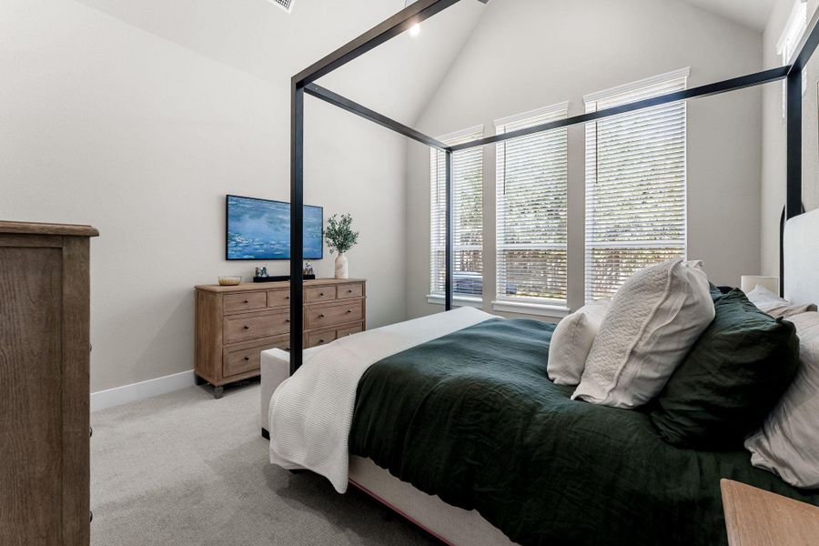 Vaulted ceiling bedroom featuring triple windows with blinds, light gray wall paint, and light gray carpeting