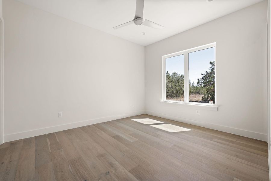 Empty room with light wood-type flooring, ceiling fan, and baseboards