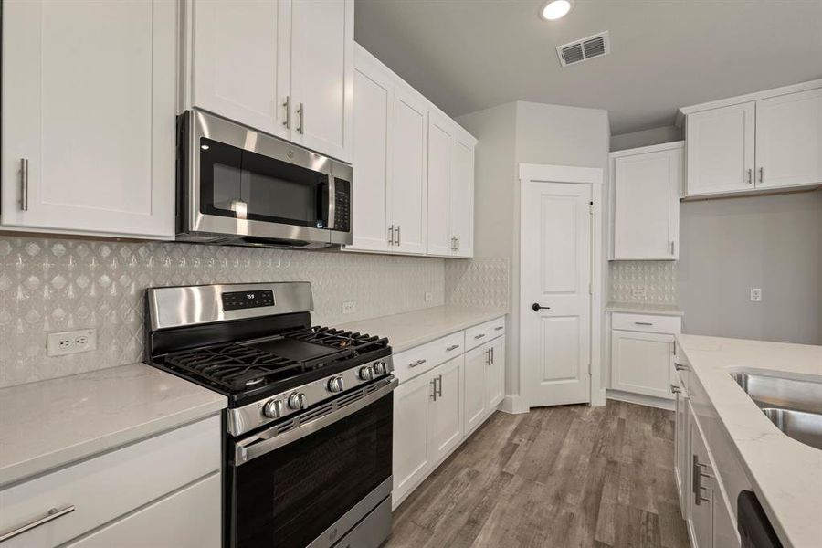 Featuring beautiful white cabinetry, gorgeous countertops, designer backsplash and stainless appliances, this kitchen offers everything you have been searching for! Featuring beautiful white cabinetry, gorgeous countertops, designer backsplash and stainless appliances, this kitchen offers everything you have been searching for!