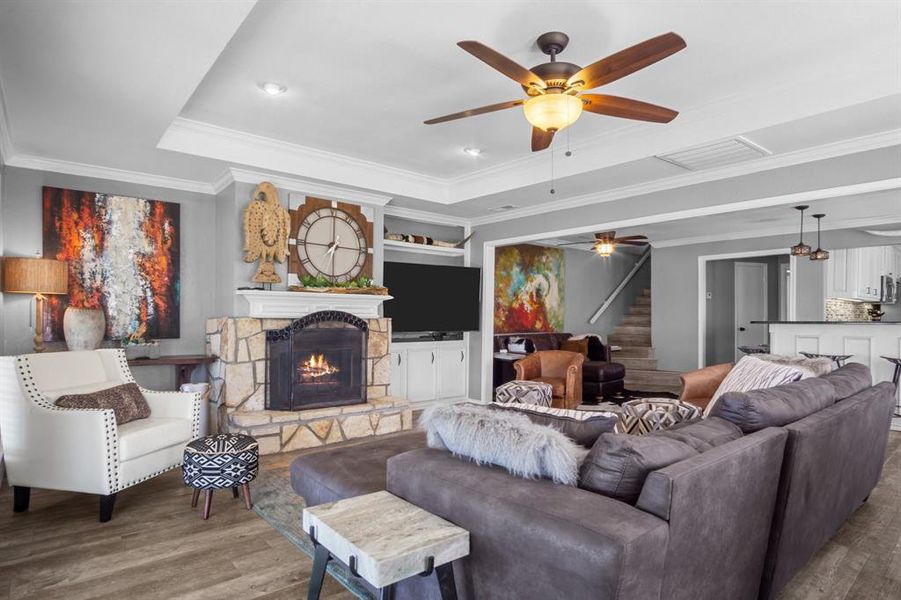 Living room with a tray ceiling, ornamental molding, a fireplace, and hardwood / wood-style floors