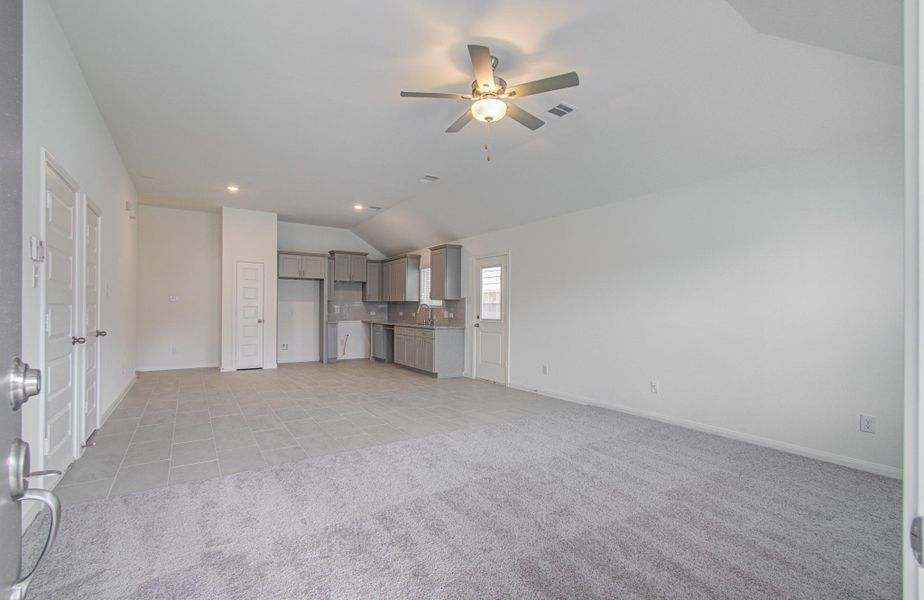 Spacious open-concept living area with modern kitchen, featuring sleek cabinetry and a ceiling fan, perfect for comfortable living and entertaining.