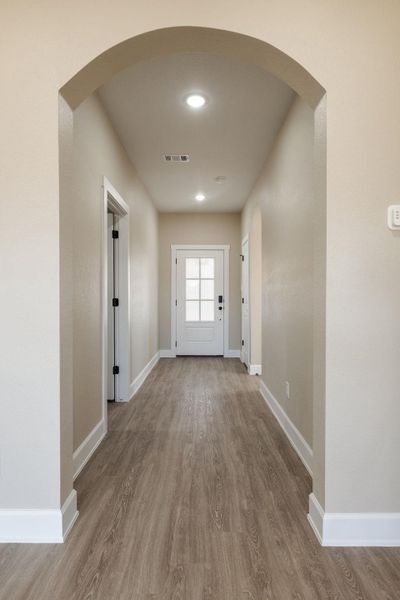 Entryway with arched walkways, wood finished floors, and recessed lighting
