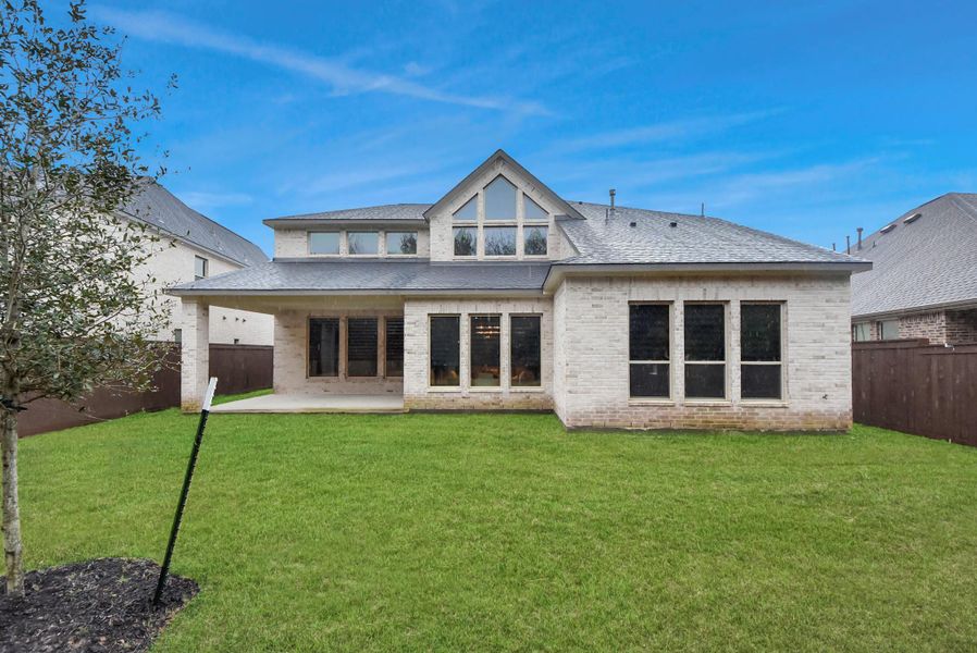 Beautiful rear elevation showcasing the extended covered patio, large upstairs windows, and spacious backyard—perfect for outdoor entertaining and enjoying the serene view.