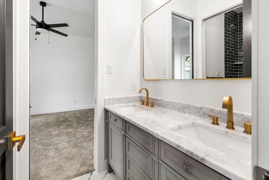 Marble vanity tops and gold fixtures elevate this modern dual-sink bathroom.