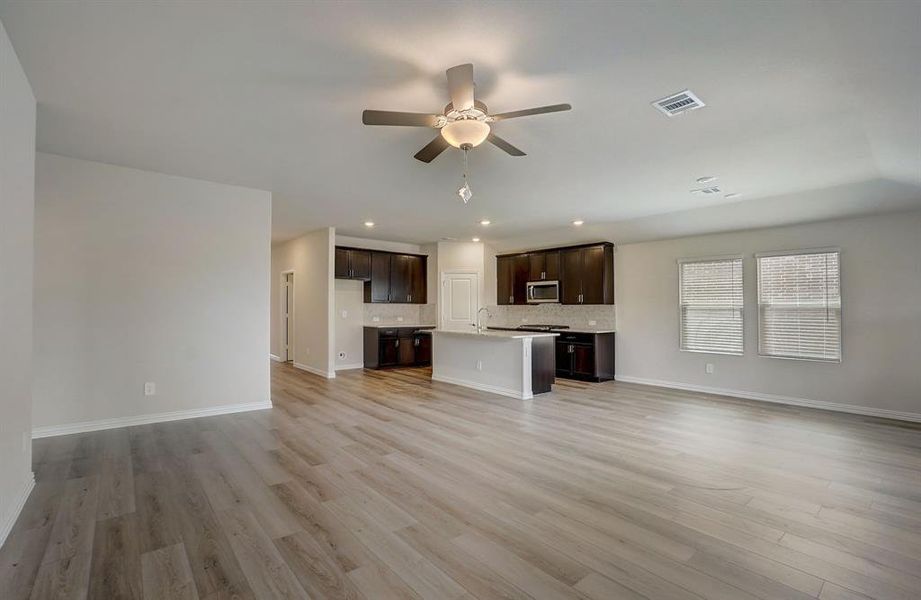 Unfurnished living room featuring ceiling fan and light wood-type flooring