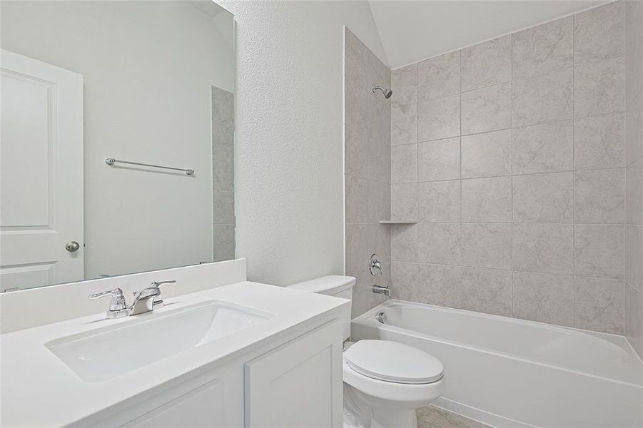 Full bathroom with toilet, tiled shower / bath combo, vanity, and vaulted ceiling