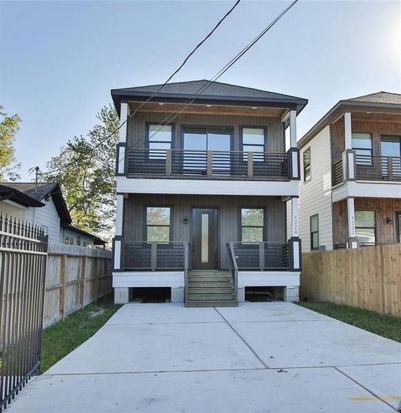 Modern two-story home with a sleek facade, featuring large windows and a spacious balcony. It includes a driveway, fenced yard, and contemporary design elements, perfect for comfortable urban living.