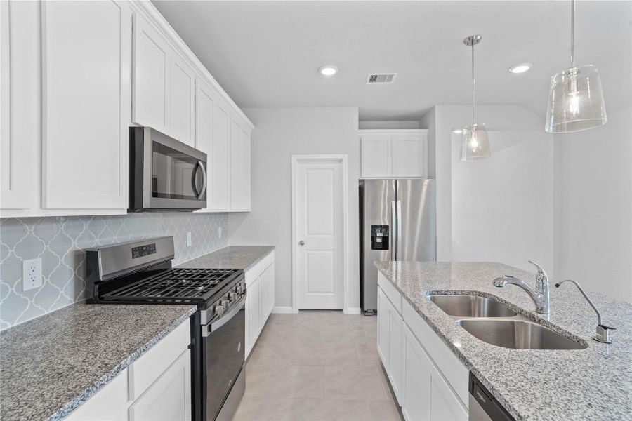 Discover this chef-ready kitchen featuring sleek, white shaker-style cabinetry, white sparkle granite countertops, and a full suite of stainless steel appliances, including an over-the-range microwave and a side-by-side refrigerator.