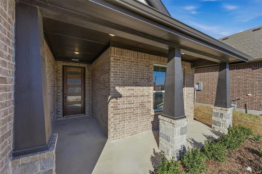 Property entrance with brick siding and covered porch