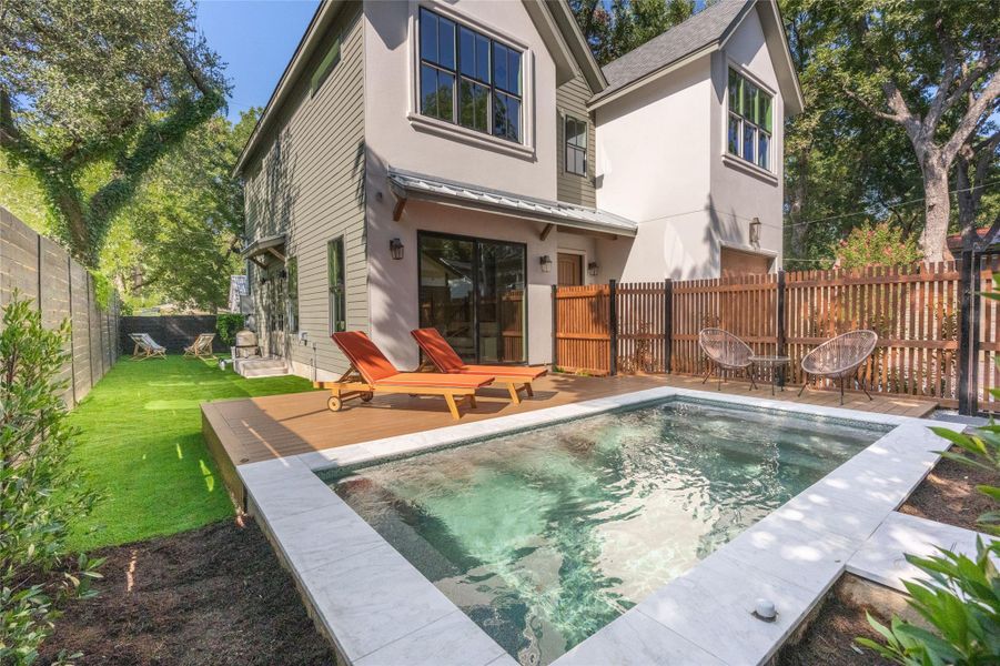 An inviting backyard oasis offers a sparkling pool, surrounding wooden deck, and a manicured lawn.