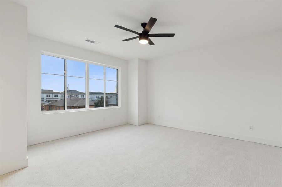 Empty room with ceiling fan and light carpet