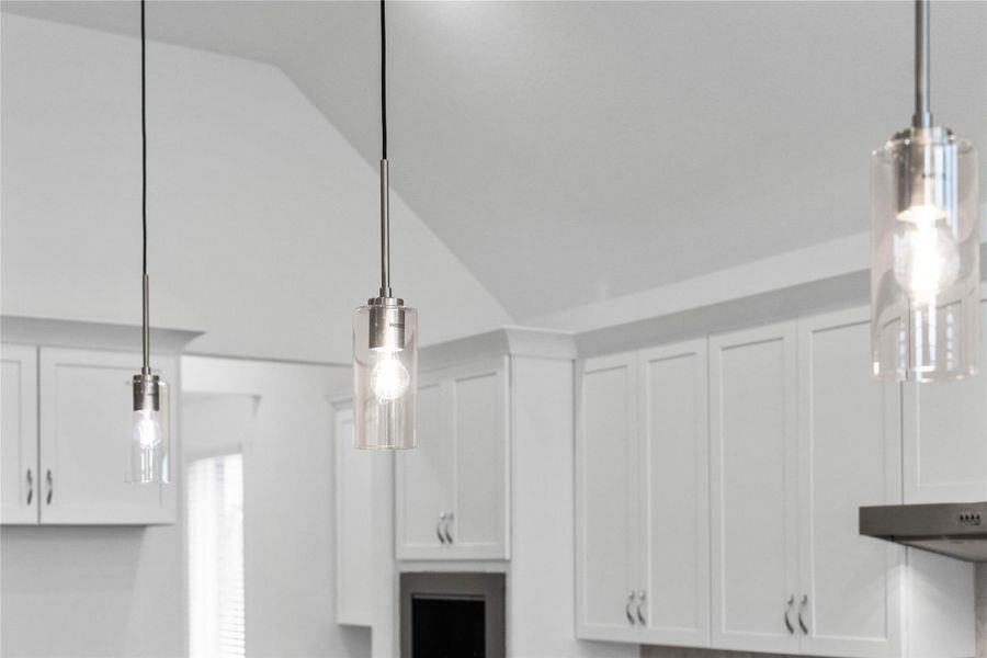 Three exquisite, clear glass pendant lights that elegantly hang above the kitchen island, providing focused task lighting and a touch of refined style. Three exquisite, clear glass pendant lights that elegantly hang above the kitchen island, providing focused task lighting and a touch of refined style.