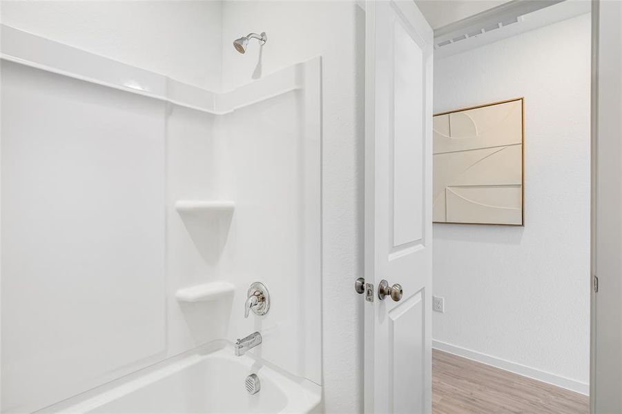 Bathroom with wood-type flooring and washtub / shower combination