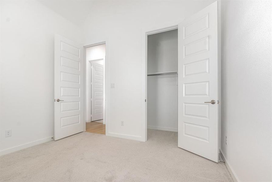 Unfurnished bedroom featuring light colored carpet and baseboards Unfurnished bedroom featuring light colored carpet and baseboards