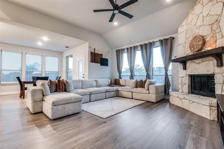 Living area featuring lofted ceiling, a ceiling fan, wood finished floors, a fireplace, and recessed lighting Living area featuring lofted ceiling, a ceiling fan, wood finished floors, a fireplace, and recessed lighting