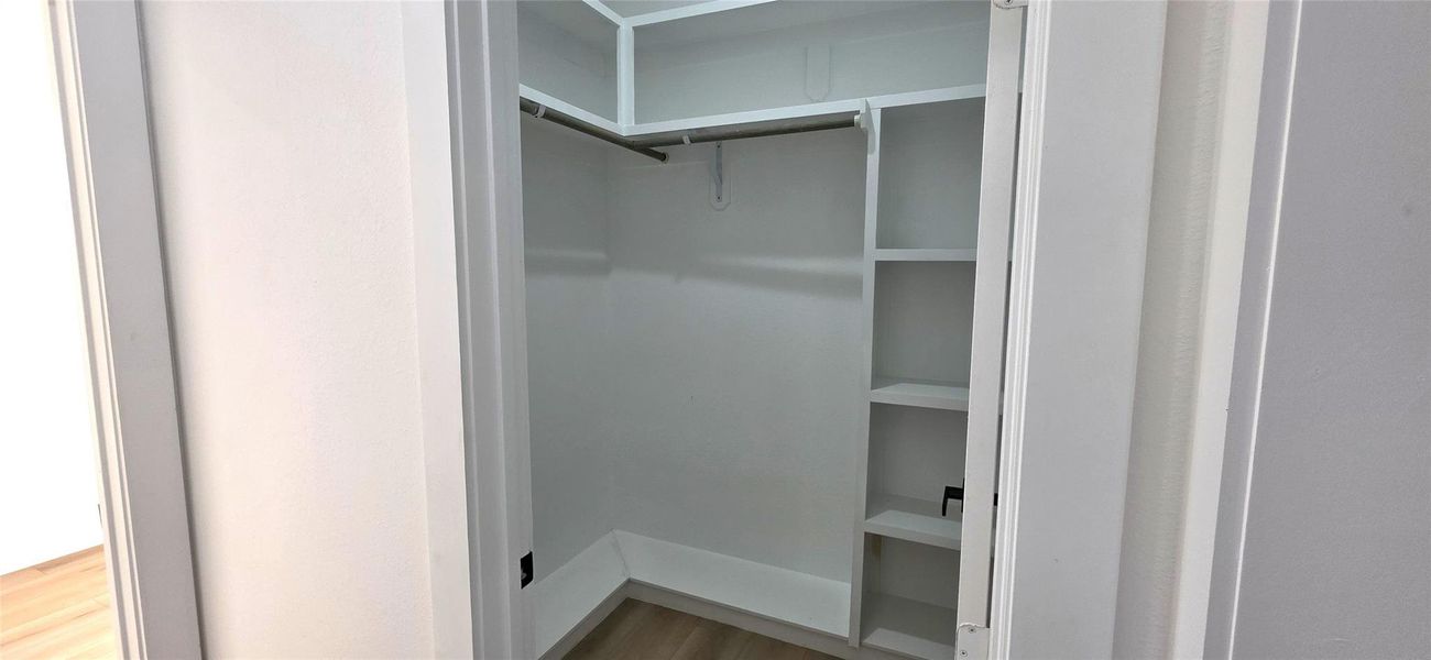 This spacious primary bedroom closet offers ample shelving and hanging space, perfect for organizing your wardrobe in style.