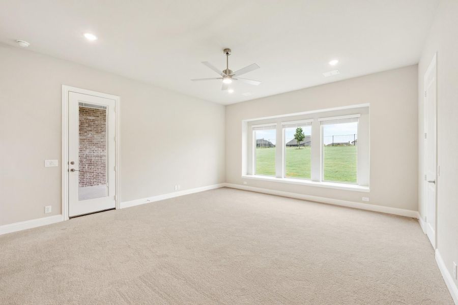 Empty room with beige carpet, ceiling fan, large window, and glass back door overlooking a yard