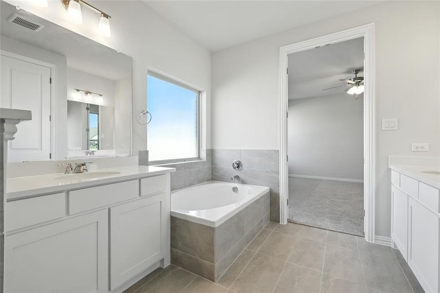 Bathroom featuring two vanities, a garden tub, and light tile patterned floors Bathroom featuring two vanities, a garden tub, and light tile patterned floors