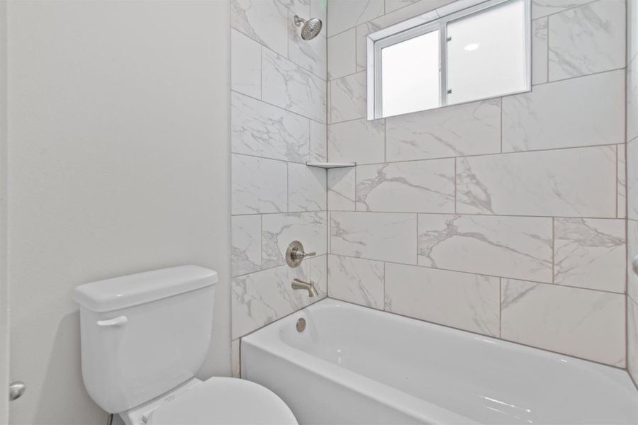 Bathroom with toilet and tiled shower / bath