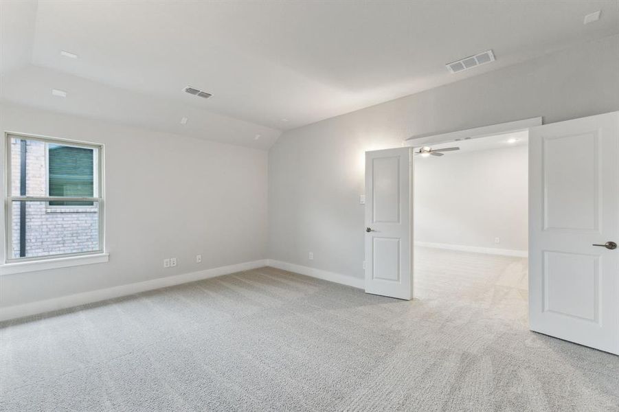 Spare room with light carpet, vaulted ceiling, and a ceiling fan